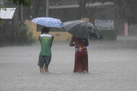 Residents wade across floodwaters caused by Typhoon Goni in Bacnotan, La Union, in northern Philippines August 22, 2015. REUTERS/TJ Corpuz