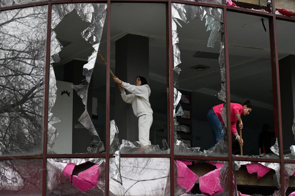 People remove shards of glass from broken windows of a building housing a beauty salon following recent shelling in  Donetsk (REUTERS)