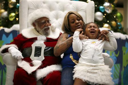 Naveah Haywood, 3, cries as she sits with African American Santa Claus Langston Patterson, 77, and her godmother Yavieshala Mitchell, 32, at Baldwin Hills Crenshaw Plaza mall in Los Angeles, California, December 16, 2013. REUTERS/Lucy Nicholson