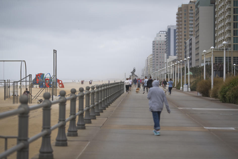 Beachgoers braved high winds while walking down the Virginia Beach Boardwalk during Tropical Storm Ophelia on Saturday, Sept. 23, 2023, in Virginia Beach, Va. Winds gusts made the sand sting against any exposed skin. (AP Photo/John C. Clark)