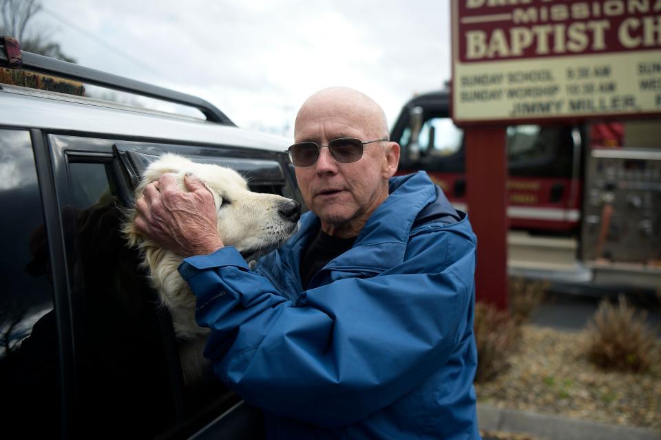 Perry Suttles is comforted by his dog, Odin, at a firefighter staging area at Dripping Springs Missionary Baptist Church in Sevierville, Tenn. on Thursday, March 31, 2022. Suttles fled his home in the Dupont area close to midnight after a neighbor woke him up alarming him of the encroaching wildfire. He has not been able to return to his home since, and called the situation terrifying.