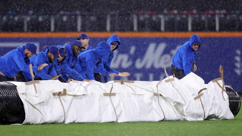 Sep 28, 2023; New York City, New York, USA; New York Mets grounds crew roll out the tarp during a rain delay during the ninth inning against the Miami Marlins at Citi Field.
