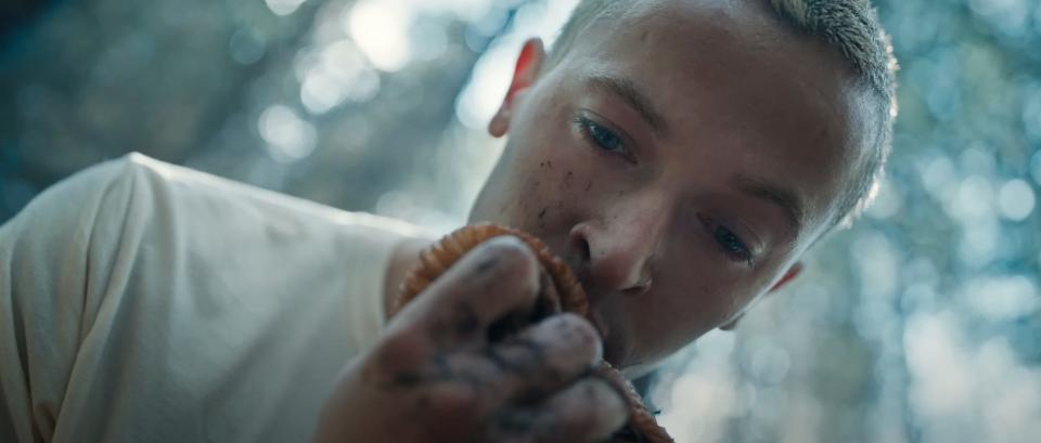 Coriolanus Snow looks at an orange shawl that he holds tightly in his fist.