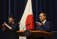 Japan's Prime Minister Yoshihide Suga (R) attends a news conference on Japan's response to the coronavirus pandemic during the Tokyo 2020 Olympic Games in Tokyo, Japan, Friday, July 30, 2021. Suga expanded a coronavirus state of emergency to four more areas in addition to Tokyo on Friday following record spikes in infections as the capital hosts the Olympics. (Issei Kato/Pool Photo via AP)