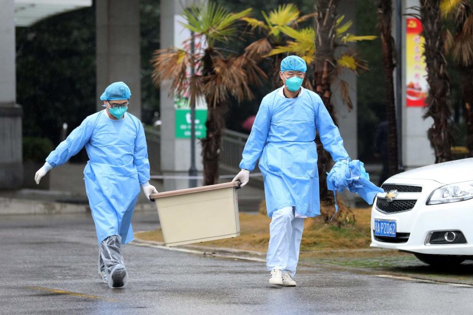 Medical staff carry a box as they walk at the Jinyintan hospital (REUTERS)