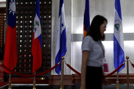 A woman walks past an El Salvador flag (R) inside the Taiwan Ministry of Foreign Affairs in Taipei, Taiwan, August 21, 2018. REUTERS/Stringer