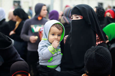 A displaced Iraqi woman carries her child at Hammam al-Alil camp, as Iraqi forces battle with Islamic State militants in Mosul, Iraq March 23, 2017. REUTERS/Khalid al Mousily