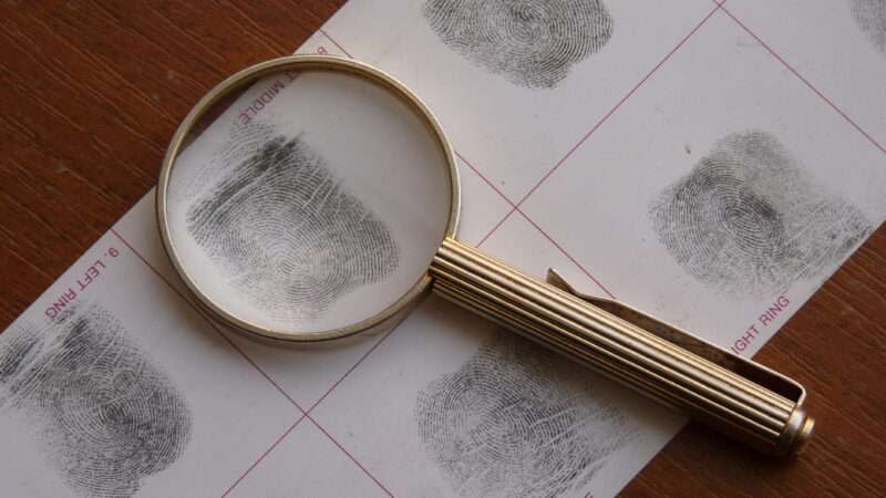 Magnifying glass sits atop a card of fingerprints.