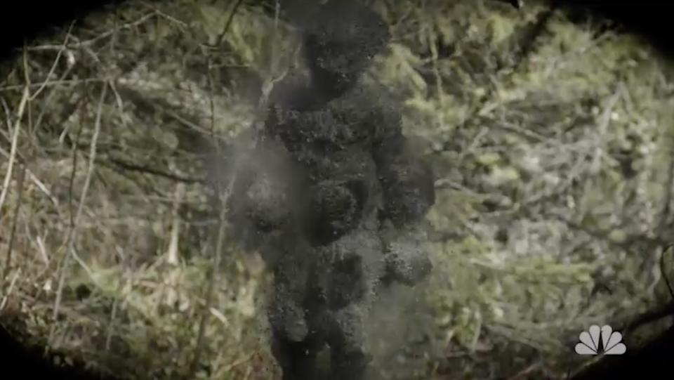 A collection of black floating things in the shape of a man walks through the woods
