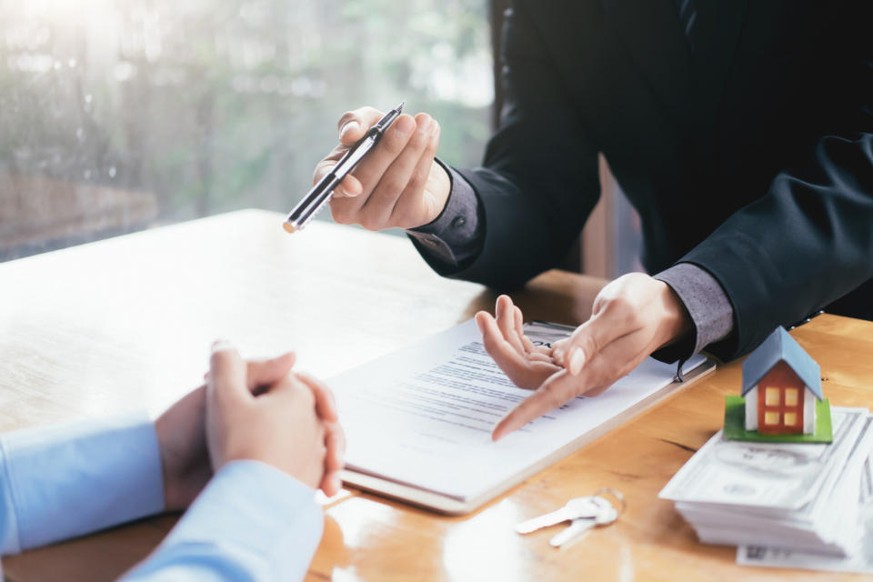 Photo of a businessman with paperwork and handing over a pen to a client