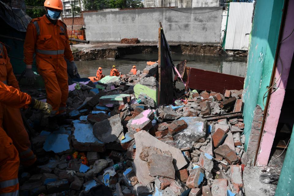National Disaster Response Force personnel inspect the remains of a shanty house after it collapsed into a canal due to heavy rains in New Delhi on July 19, 2020. (Photo by Sajjad HUSSAIN / AFP) (Photo by SAJJAD HUSSAIN/AFP via Getty Images)
