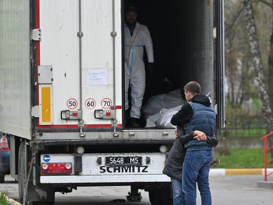 Local residents react in front of a refrigerated lorry containing bodies of victims in Bucha, northwest of Kyiv, on April 28, 2022, amid Russian invasion of Ukraine.