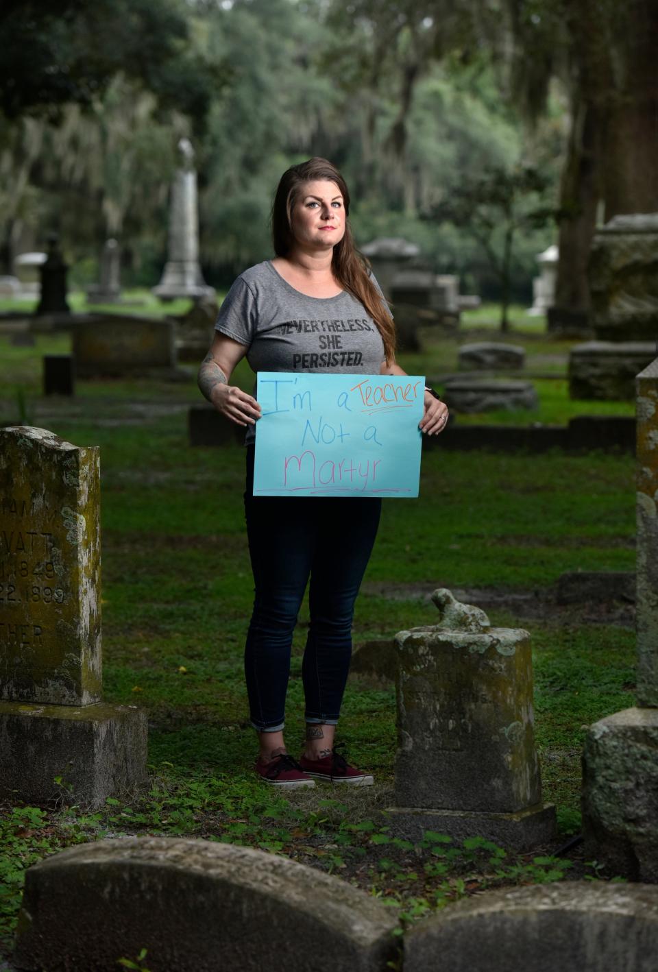 Whitney Reddick, a special education teacher in Jacksonville, Fla., holds a sign that says "I'm a teacher, not a martyr" after participating in a march protesting the opening of schools during the pandemic that ended at a cemetery.