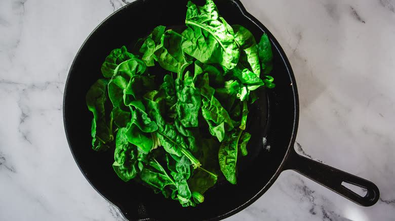 Uncooked spinach in cast iron pan