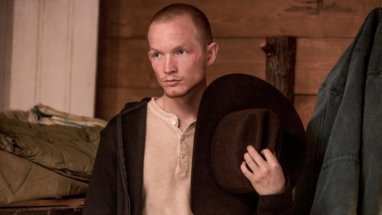  Jefferson White as Jimmy holding his cowboy hat to his chest in Yellowstone. 