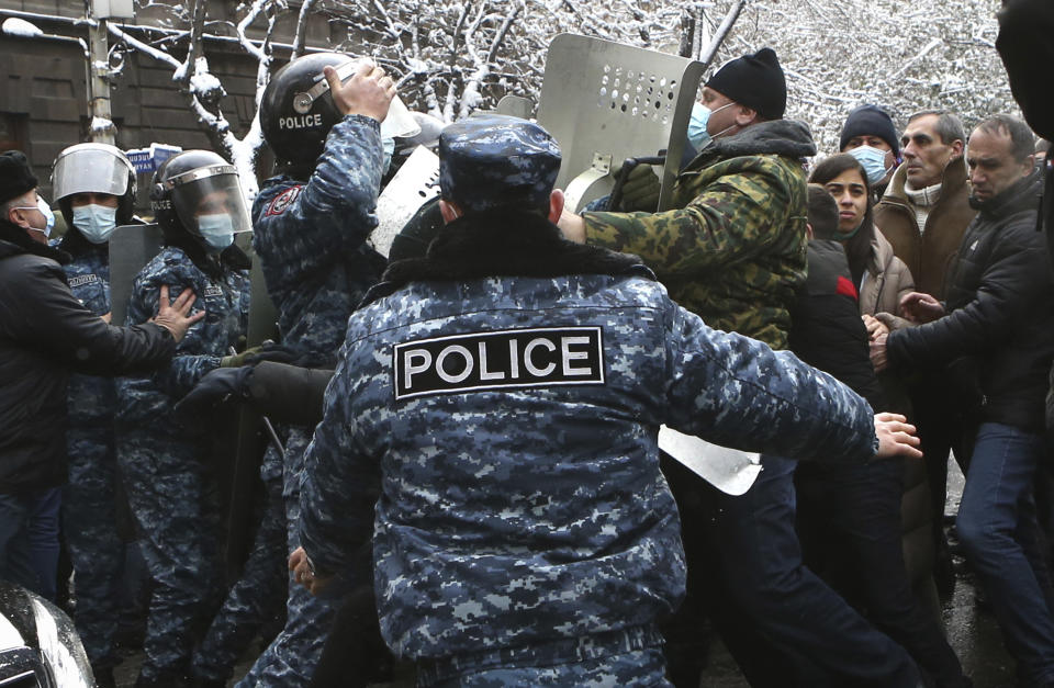 Demonstrators scuffle with Armenian police during a rally to pressure Armenian Prime Minister Nikol Pashinyan to resign over a peace deal with neighboring Azerbaijan on Republic Square in Yerevan, Armenia, Thursday, Dec. 24, 2020. Armenian opposition politicians and their supporters have been protesting for weeks, demanding the prime minister's resignation over his handling of the Nagorno-Karabakh conflict with Azerbaijan. (Vahram Baghdasaryan, Photolure via AP)