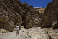 Tourists hike the Golden Canyon trail on July 11, 2023, in Death Valley National Park, Calif. A 71-year-old Los Angeles-area man died at the trailhead on Tuesday, July 18, as temperatures reached 121 degrees (49 Celsius) or higher and rangers suspect heat was a factor, the National Park Service said in a statement Wednesday. (AP Photo/Ty ONeil)