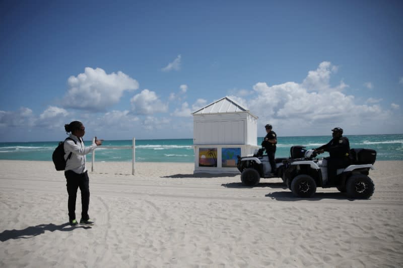 Police officers ask a man to leave after local authorities order the closing of all the beaches in Miami-Dade county for precaution due to coronavirus disease (COVID-19) spread, in Miami Beach, Florida, U.S.