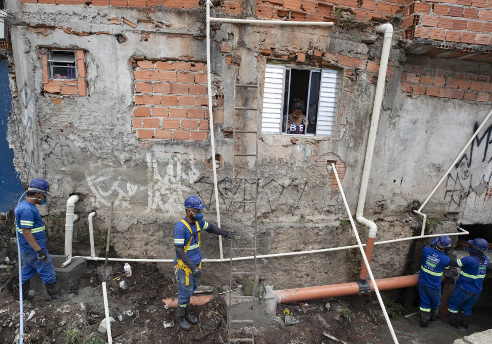 Men work to build a sewage system at the Americanopolis community, located near the Pinheiros River in Sao Paulo, Brazil, Thursday, Oct. 22, 2020. Affected by domestic sewage and solid wastes discharges for years, Sao Paulo's state government is again trying to clean the Pinheiros River, considered one of the most polluted in Brazil. (AP Photo/Andre Penner)