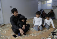 Zana Mamand, left, the brother of Twana Mamand who was lost at sea in the English Channel trying to get to Britain, sits with family members, at their house in Ranya, Iraq, Tuesday, Nov. 30, 2021. Zana wiped away tears and vowed to take revenge against the family of the smuggler who arranged for his brother’s journey. (AP Photo/Khalid Mohammed)