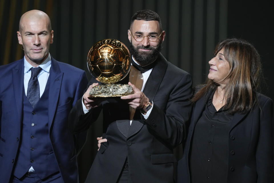 El delantero del Real Madrid Karim Benzema muestra el Balón de Oro 2022 junto a su madre Wahida y Zinedine Zidane, el lunes 17 de octubre de 2022, en París. (AP Foto/Francois Mori)