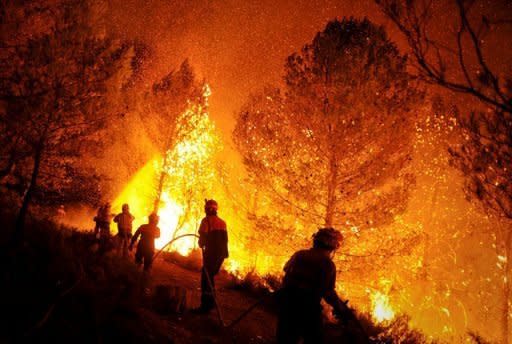 Firefighters from the towns of Alcoy and Elda try to extinguish a fire in Torre de Macanes near Alicante. Wildfires drove thousands of people from their homes near a rare nature reserve in Spain's Canary Islands Monday after a separate mainland blaze killed two, authorities said