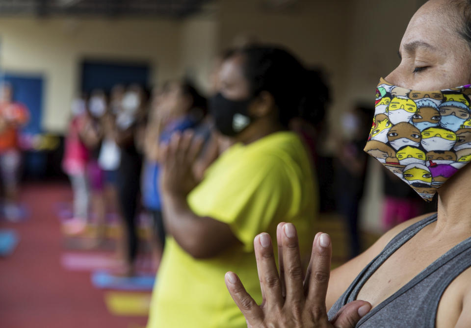Residents take part in a free yoga class sponsored by the "Treino na Laje" project that aims to recover people’s self-esteem through yoga, in Capao Redondo favela, in Sao Paulo, Brazil, Saturday, Oct. 24, 2020, as restrictions related to COVID-19 pandemic are eased. The project also distributes donated food and toys for poor children, performs social actions and administers free sports classes. (AP Photo/Carla Carniel)