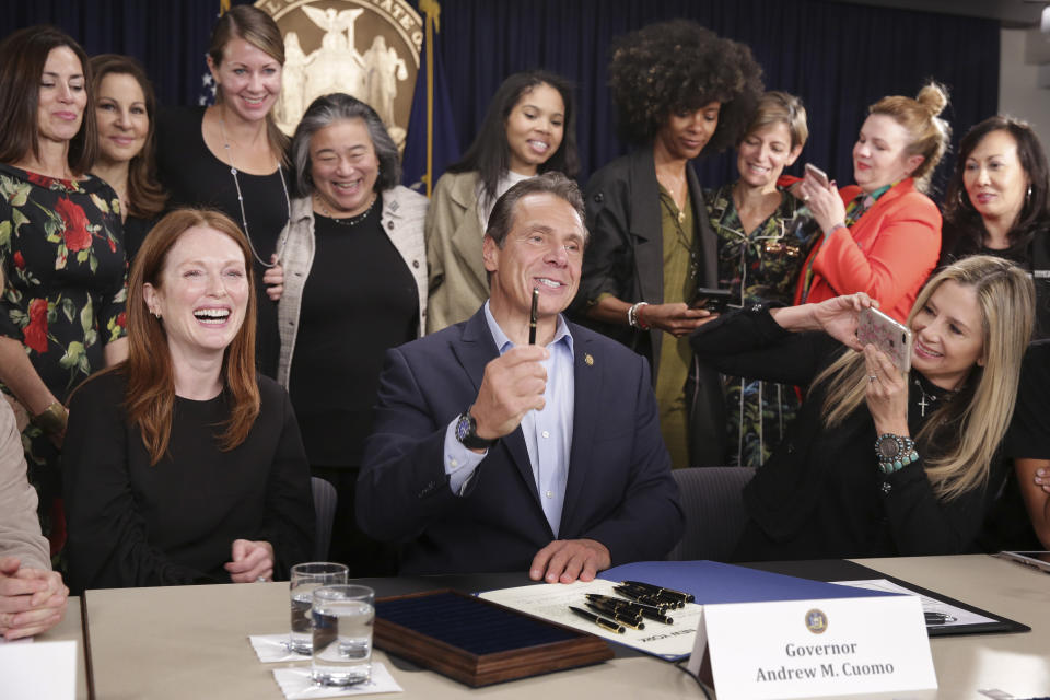 Surrounded by supporters and activists, New York Gov. Andrew Cuomo signs a bill that increases the statute of limitations in rape cases during a bill signing ceremony in New York, Wednesday, Sept. 18, 2019. Actresses Julianne Moore, left, and Mira Sorvino, right, were there as supporters of the bill and members of the Time's Up movement, which advocates for women's rights. (AP Photo/Seth Wenig)