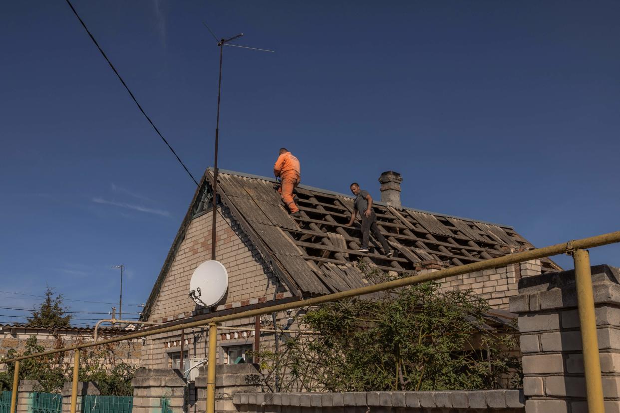 Men repair the roof of a house that was damaged during an overnight Russian attack in the southern city of Kherson (AFP via Getty Images)