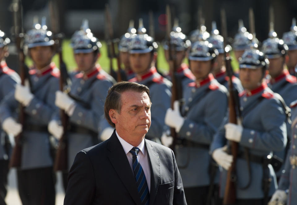 Brazil's President Jair Bolsonaro walks past the "Granaderos" presidential guard during a welcoming ceremony at La Moneda, in Santiago, Chile, Saturday, March 23, 2019. Bolsonaro is on the second day of his two-day visit. (AP Photo/Esteban Felix)