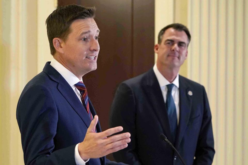 Oklahoma Gov. Kevin Stitt, right, looks on as Lt. Gov. Matt Pinnell, left, speaks at a news conference Friday, April 29, 2022, in Oklahoma City. Stitt said he has accepted the resignation of Oklahoma's Tourism and Recreation Department Executive Director Jerry Winchester and that the state has filed a lawsuit against the operator of six state park restaurants. (AP Photo/Sue Ogrocki)