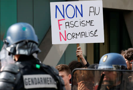 A demonstrator holds a placard with the message, "No to normalised Fascism" near gendarmes who secure an area at the traditional May Day labour union march in Paris, France, May 1, 2017. REUTERS/Gonzalo Fuentes