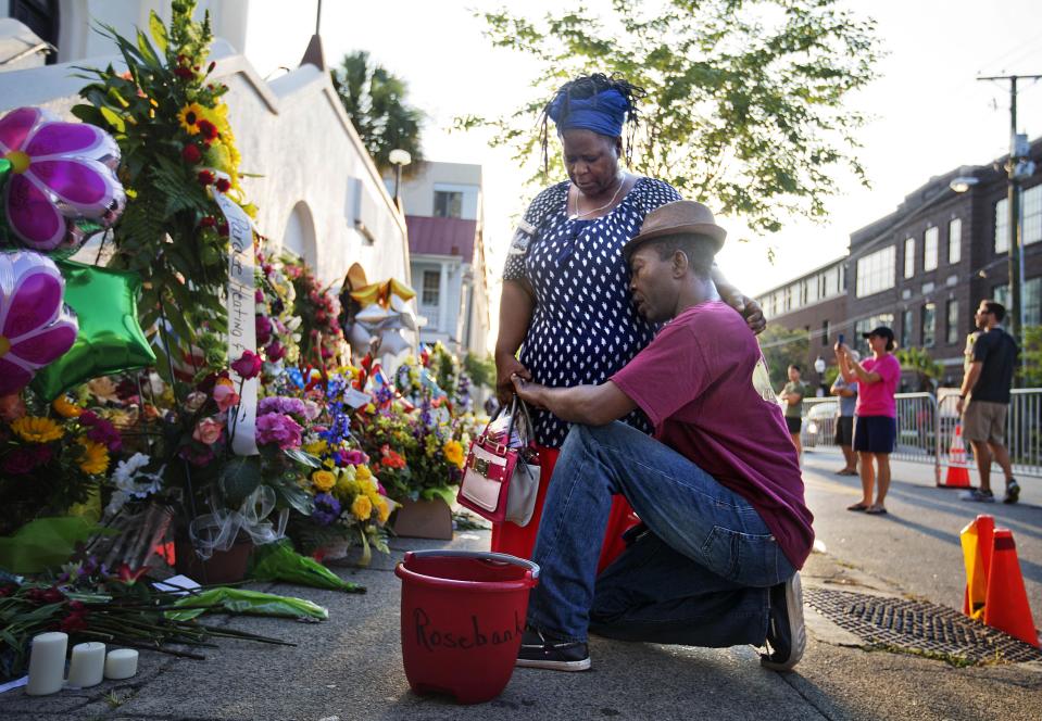 FILE- In this June 20, 2015, file photo, Allen Sanders, right, kneels next to his wife, Georgette, both of McClellanville, S.C., as they pray at a sidewalk memorial in memory of the shooting victims in front of Emanuel AME Church in Charleston, S.C. One big change happened in conservative South Carolina after a racist gunman killed nine black people during a Bible study five years ago -- the Confederate flag came down. But since then, hundreds of other monuments and buildings named for Civil War figures, virulent racists and even a gynecologist who did painful, disfiguring medical experiments on African American women remain.