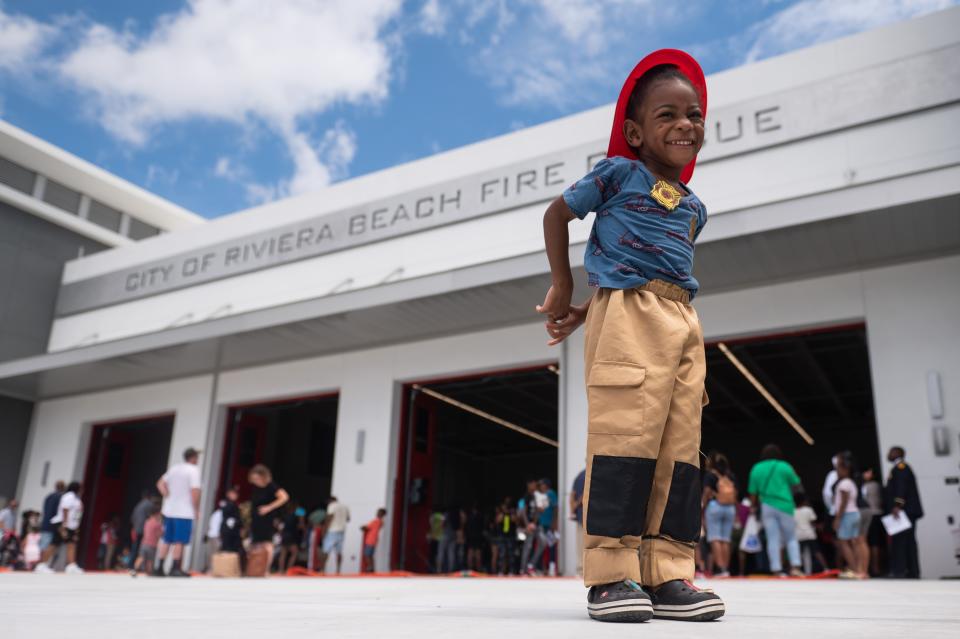 Oakland Barnaby, a 3-year-old from West Palm Beach, smiles at his mother while wearing a plastic firefighter hat and badge in front of Riviera Beach's newest fire station, Station 88. The 31,000 square foot, $20 million building houses Riviera Beach Fire Rescue trucks, decontamination facilities, a memorial honoring fallen firefighters from 9/11 and more.