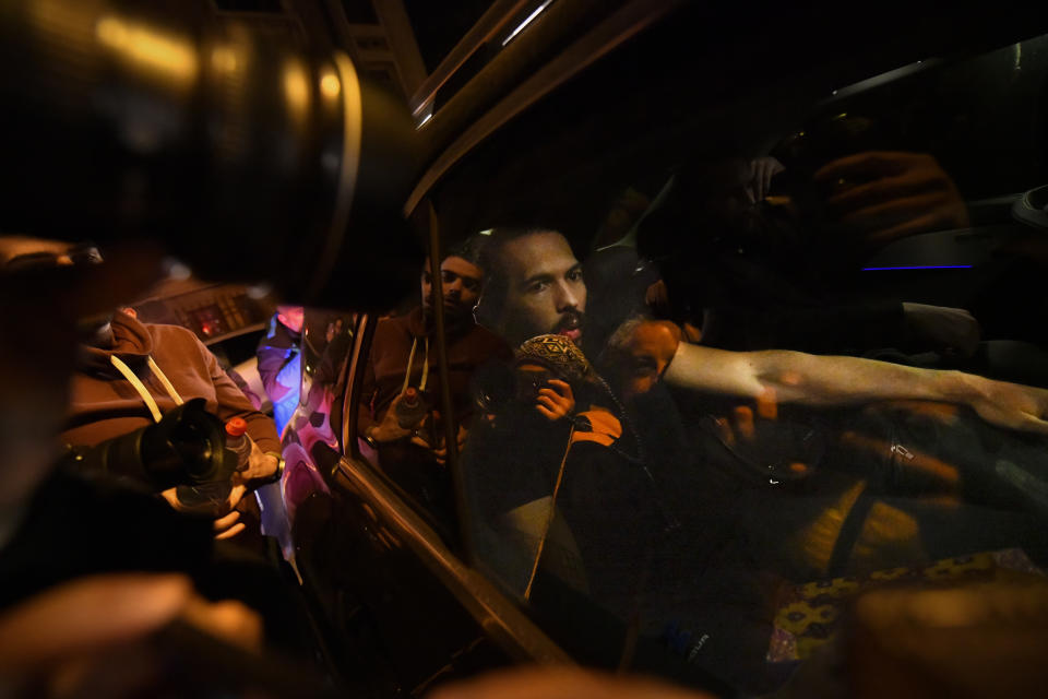 Andrew Tate sits in a car after leaving a police detention facility in Bucharest, Romania, after his release from prison on Friday March 31, 2023. An official on Friday said Tate, the divisive internet personality who has spent months in a Romanian jail on suspicion of organized crime and human trafficking, has won an appeal to replace his detention with house arrest. (AP Photo/Alexandru Dobre)