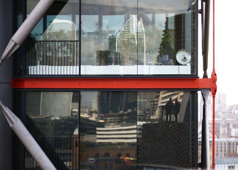 Visitors to the Viewing Level at the Tate Modern gallery are reflected in the window of a luxury block of flats in London