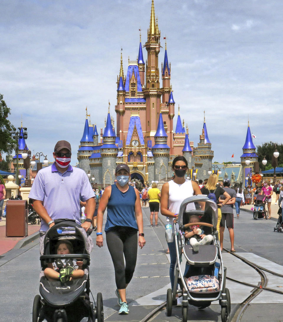 Guests walk on Main Street, U.S.A., in front of Cinderella Castle in the Magic Kingdom at Walt Disney World, in Lake Buena Vista, Fla., Wednesday, Sept. 30, 2020. The Walt Disney Co. announced Tuesday that it is planning to lay off 28,000 workers in its theme parks division in California and Florida. The company has been squeezed by limits on attendance at its parks and other restrictions due to the pandemic. (Joe Burbank/Orlando Sentinel via AP)