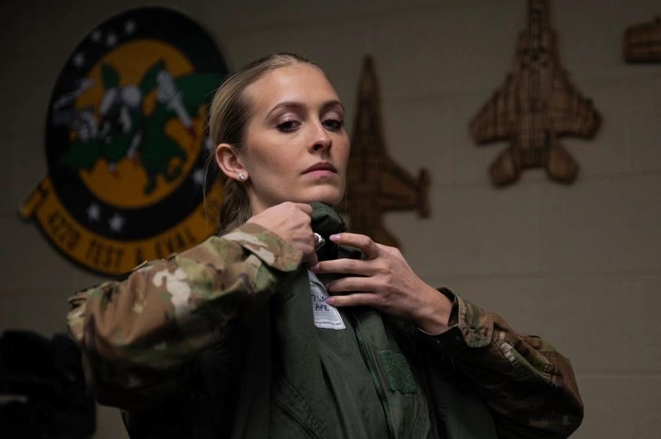 A woman holds a flight suit against her body to check the fit