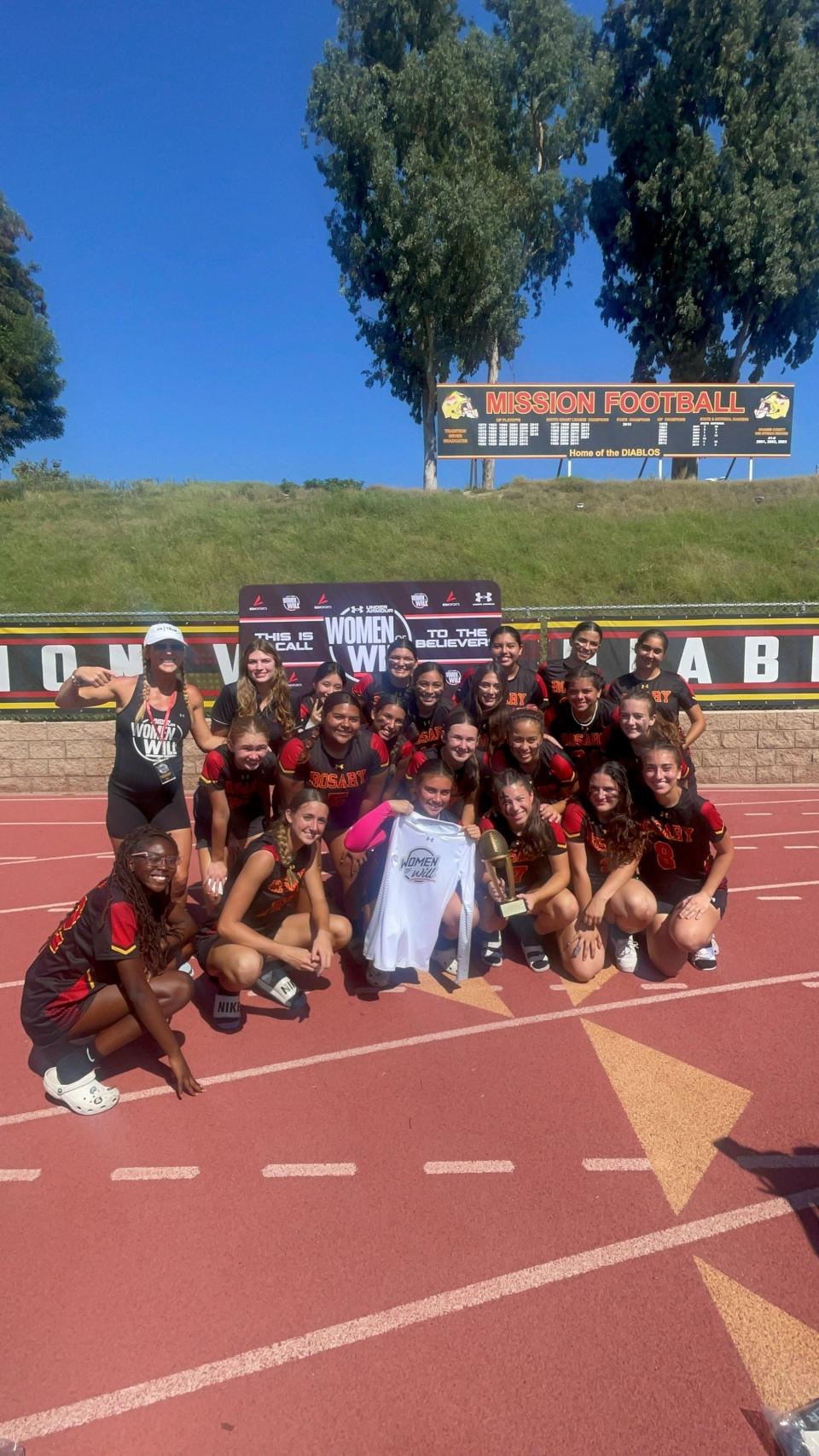 Emmy Walton, account manager for Women of Will, poses with the Rosary Academy (Fullerton, Calif.) flag football team, which won a tournament last month at Mission Viejo High school.
