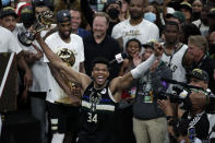 FILE - Milwaukee Bucks forward Giannis Antetokounmpo (34) celebrates with the MVP trophy, as teammates hold the championship trophy, after defeating the Phoenix Suns in Game 6 of basketball's NBA Finals Tuesday, July 20, 2021, in Milwaukee. The Bucks won 105-98. (AP Photo/Aaron Gash, File)