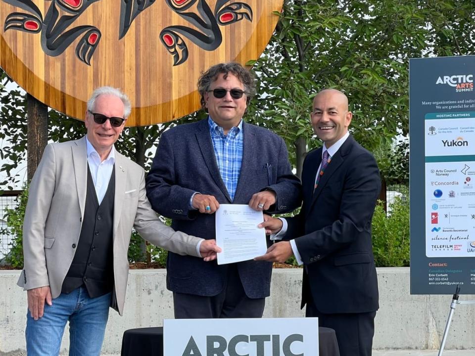 Director and CEO of the Canada Council for the Arts Simon Brault, Jesse Wente Chairperson of the Canada Council for the Arts and Yukon's Minister of Tourism and Culture Ranj Pillai hold the new Memorandum of Understanding between the two organizations on Wednesday morning. (Sissi De Flaviis/CBC - image credit)