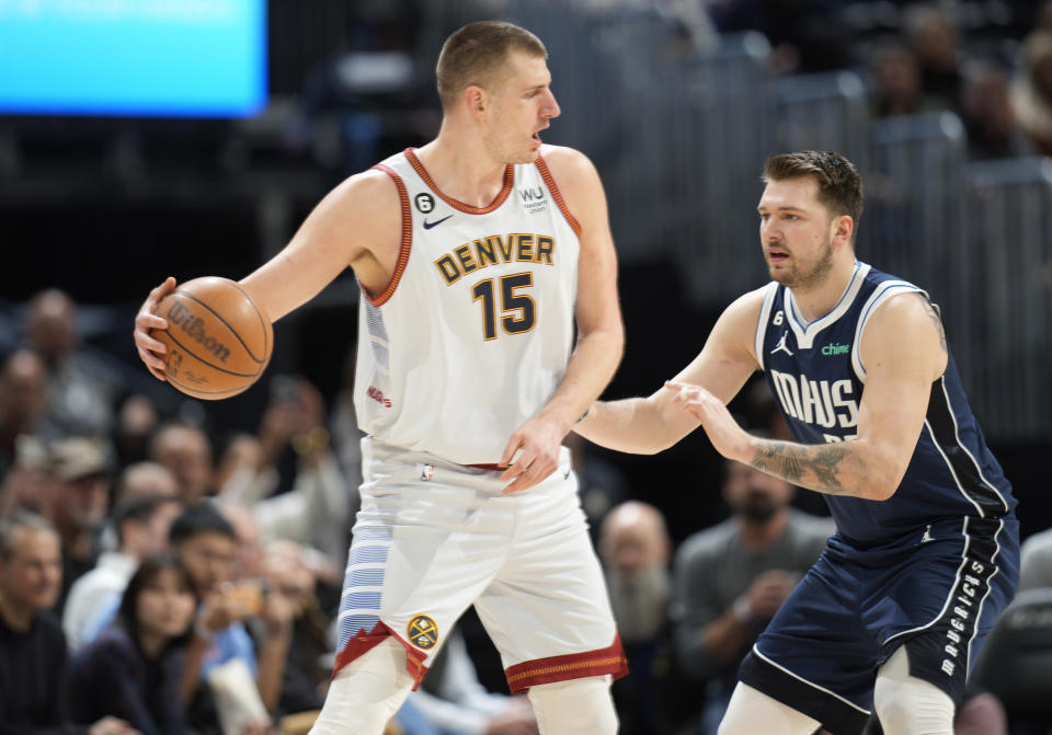 Denver Nuggets center Nikola Jokic, left, looks to pass the ball as Dallas Mavericks guard Luka Doncic defends in the first half of an NBA basketball game Wednesday, Feb. 15, 2023, in Denver. (AP Photo/David Zalubowski)