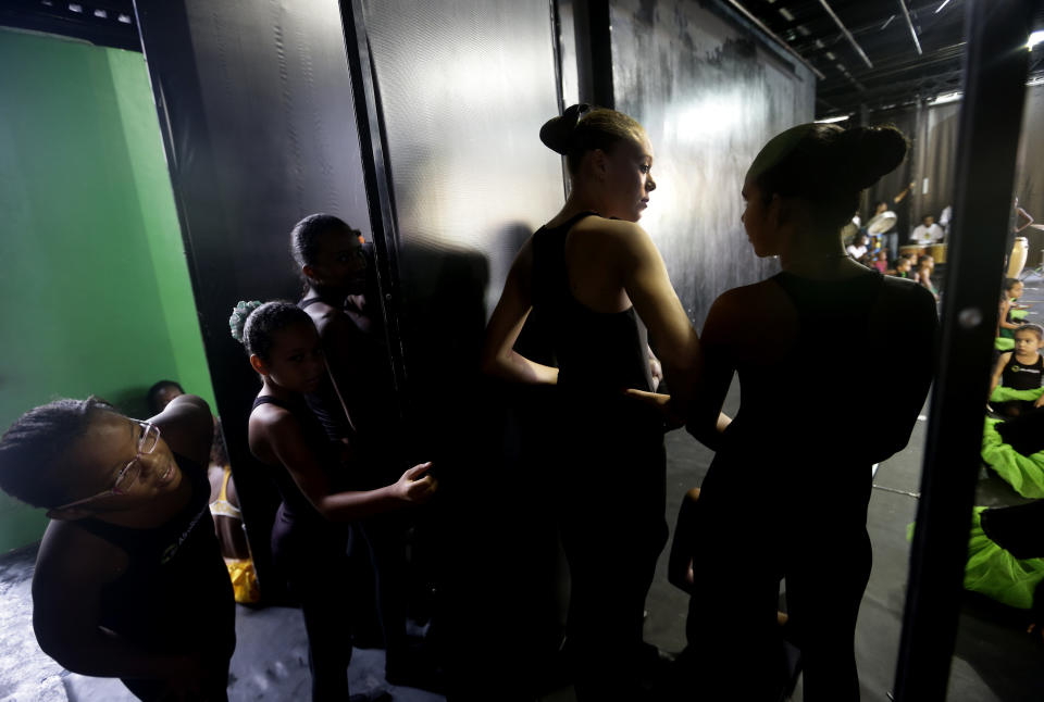 Dancers from the Afro Reggae cultural center peer from backstage before performing before members of London's Royal Opera House in the Vigario Geral slum in Rio de Janeiro, Brazil, Saturday, March 2, 2013. This past week Royal Ballet dancers shared their knowledge and advice with promising artists during an education symposium between the company and the cultural arts center Afro Reggae. (AP Photo/Silvia Izquierdo)