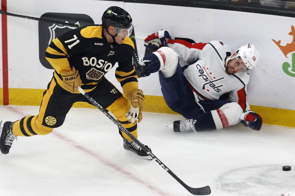 Washington Capitals' Erik Gustafsson crashes into the boards while battling Boston Bruins' Taylor Hall (71) during the first period of an NHL hockey game, Saturday, Feb. 11, 2023, in Boston. (AP Photo/Michael Dwyer)