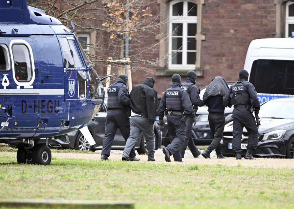 Two people are led from a helicopter to a car by police officers at a helipad in Karlsruhe, Germany, Friday Dec. 15, 2023. Denmark and Germany announced Thursday arrests of several terror suspects, including alleged Hamas members suspected of plotting attacks on Jews and Jewish institutions in Europe over the ongoing Israel-Hamas war. (Uli Deck/dpa via AP)