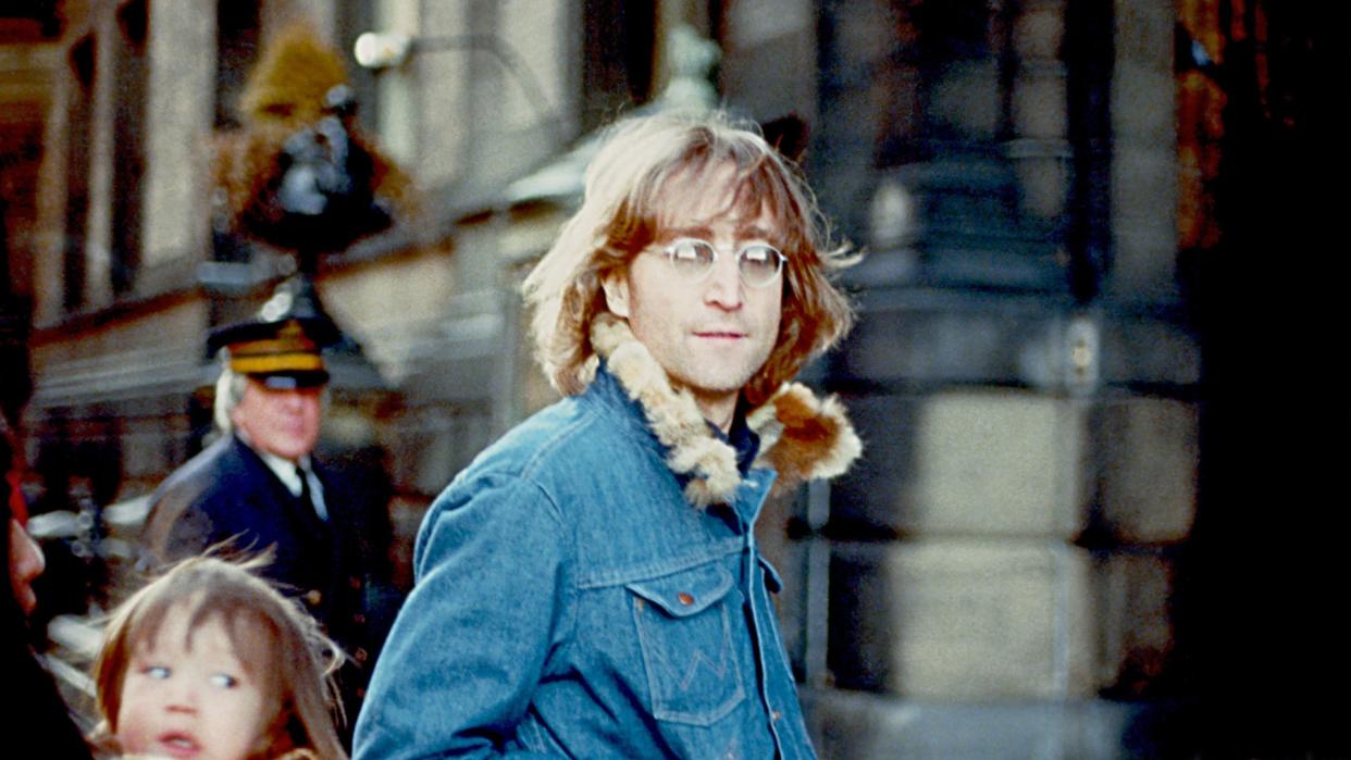  John Lennon in 1977 outside the Dakota building where he lived with his wife and son in New York . 