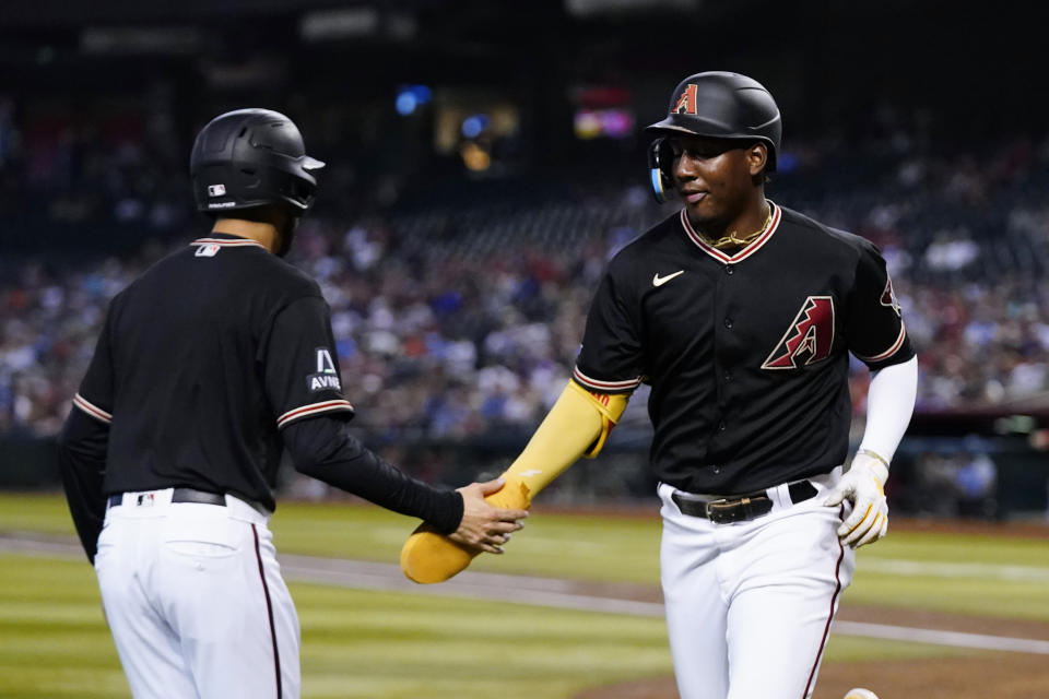 Arizona Diamondbacks' Geraldo Perdomo, right, celebrates with the team's bat boy, left, after scoring against the St. Louis Cardinals during the first inning of a baseball game Monday, July 24, 2023, in Phoenix. (AP Photo/Ross D. Franklin)