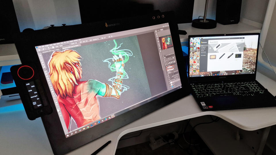 A photo of the Xencelabs Pen Display 24 on a desk with a laptop and an art piece on screen