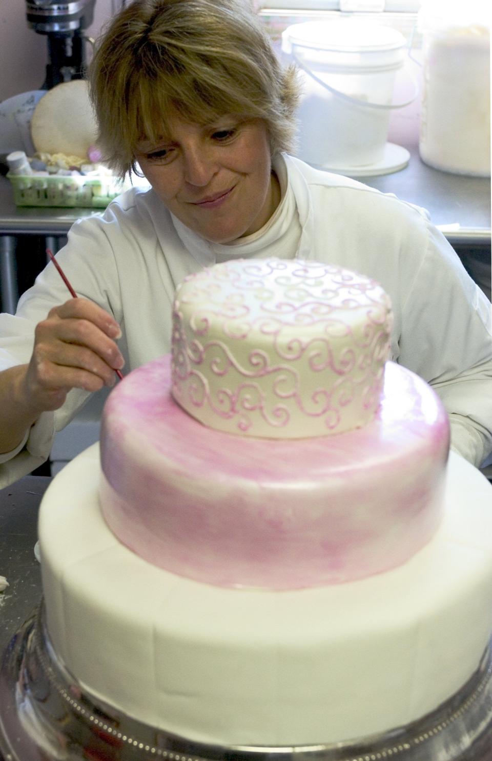 Pastry chef Lisa Raffael of Falmouth, who has been crafting cakes for decades, works on a three-tier pearlized fondant wedding cake early in her career.