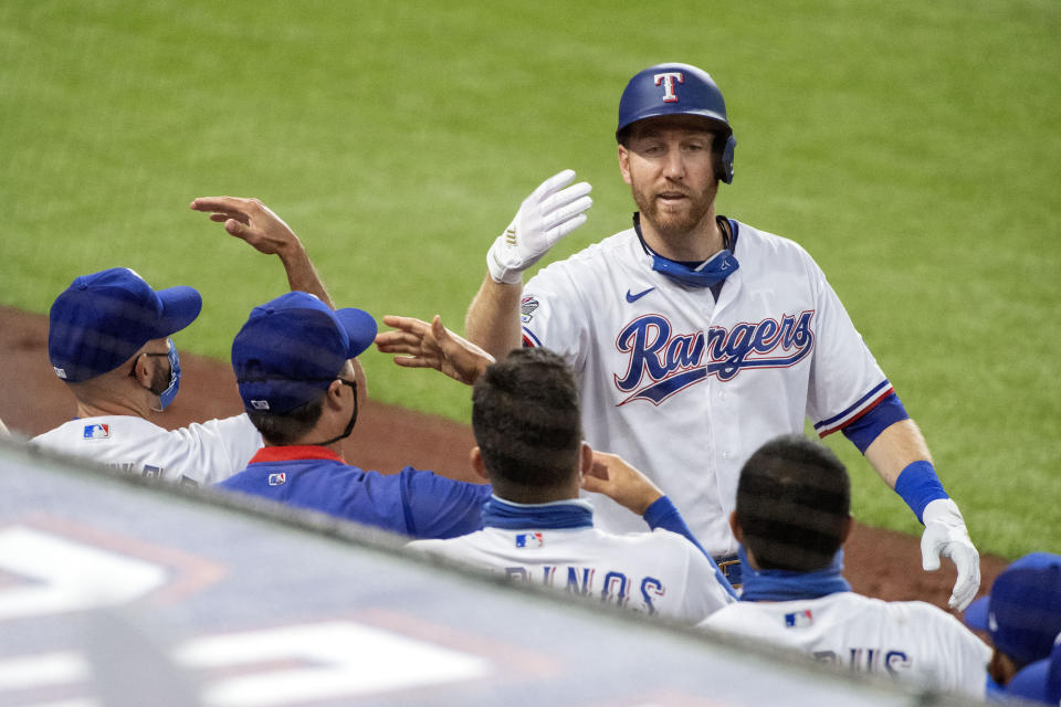 Texas Rangers' Todd Frazier celebrates with teammates after his solo home run off of Arizona Diamondbacks starting pitcher Madison Bumgarner during the fourth inning of a baseball game Wednesday, July 29, 2020, in Arlington, Texas. (AP Photo/Jeffrey McWhorter)